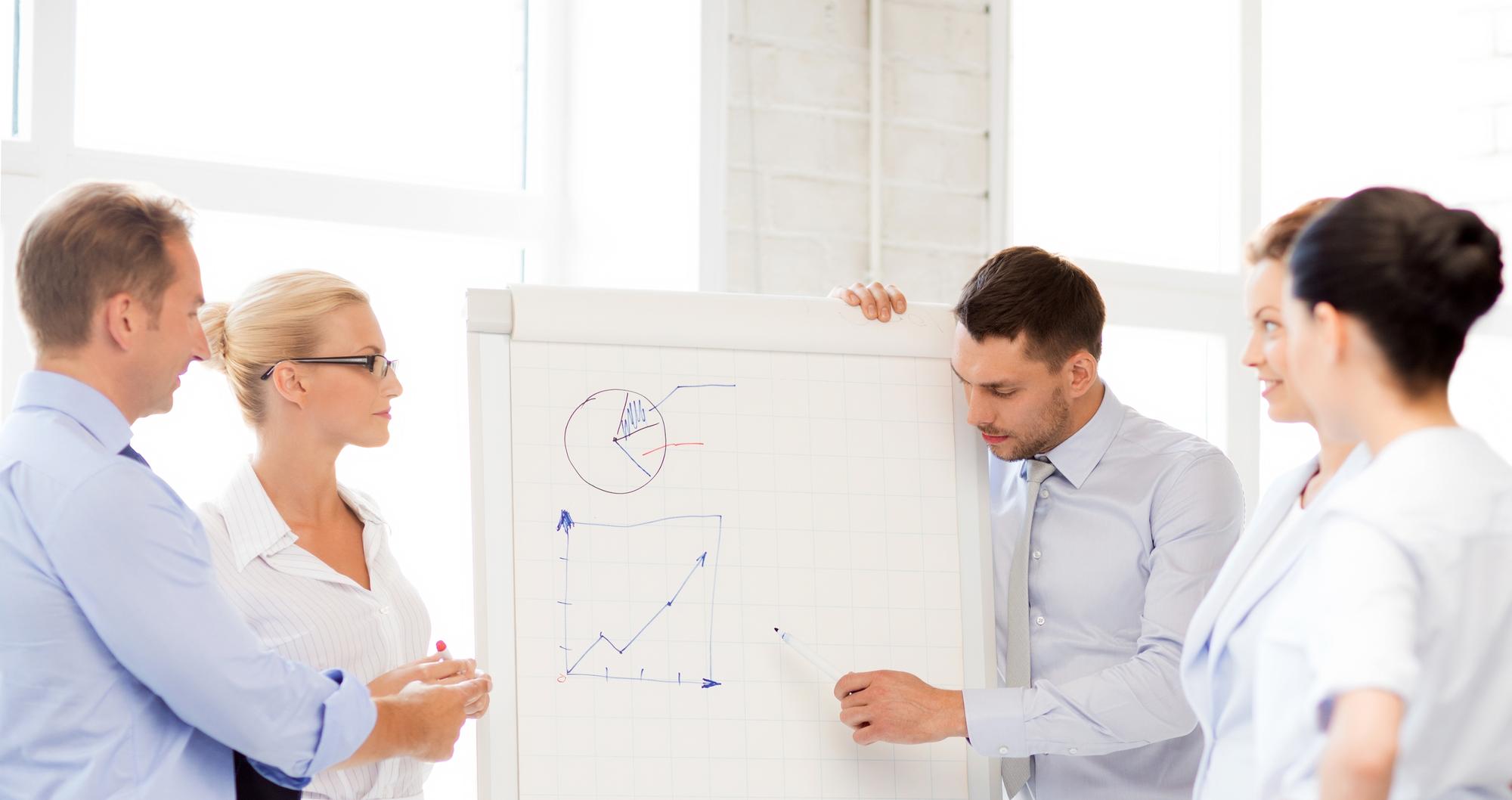 Kleines Team in Gespräch vor Whiteboard